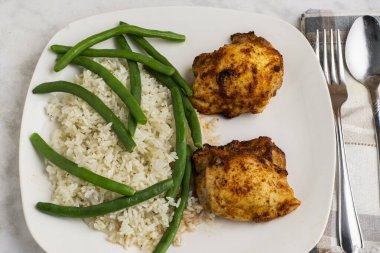  Pirinç ve yeşil fasulyeyle servis edilen tavuk butları.