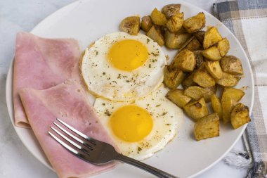 Maydanoz ve biberli sahanda yumurta dilimlenmiş jambon ve patates kızartması.