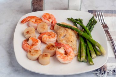 kuşkonmaz, istiridye ve karides ile servis edilen mezgit.