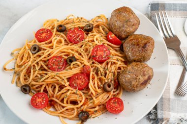  Domatesli spagetti üstü, zeytin ve kısmen İtalyan köfteleriyle servis edilir.