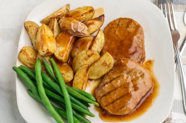  Yeşil fasulyeli salisbury bifteği ve soslu patates dilimleri.