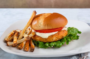 Marullu somon burger, domates ve patates kızartmasıyla servis edilen tarter sosu.