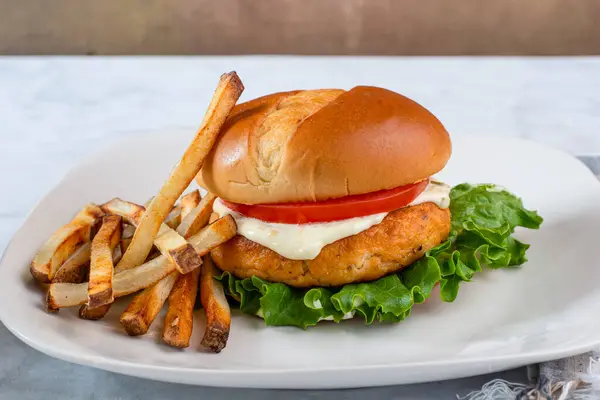 Marullu somon burger, domates ve patates kızartmasıyla servis edilen tarter sosu.