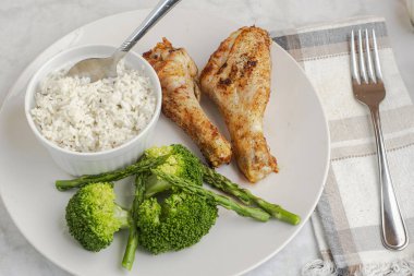 Brokoli ve aspaagusla servis edilen tavuk budu ve pilav.