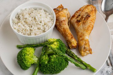 Brokoli ve aspaagusla servis edilen tavuk budu ve pilav.