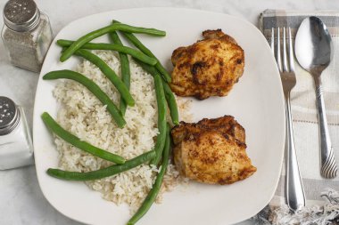  Pirinç ve yeşil fasulyeyle servis edilen tavuk butları.