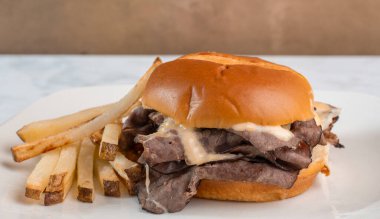 Kızarmış biftekli sandviç, erimiş peynir ve patates kızartması.