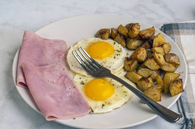 Maydanoz ve biberli sahanda yumurta dilimlenmiş jambon ve patates kızartması.