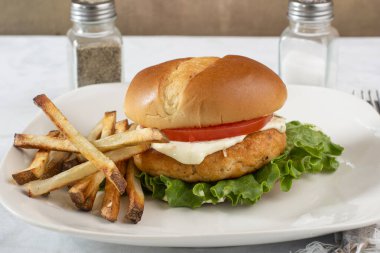 Marullu somon burger, domates ve patates kızartmasıyla servis edilen tarter sosu.