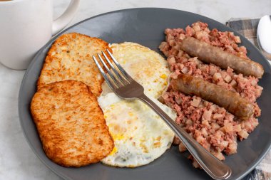 Kahvaltıda sosis ve mücver ile servis edilen mısır biftekli yumurta.