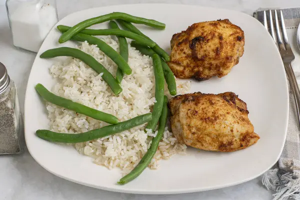  Pirinç ve yeşil fasulyeyle servis edilen tavuk butları.