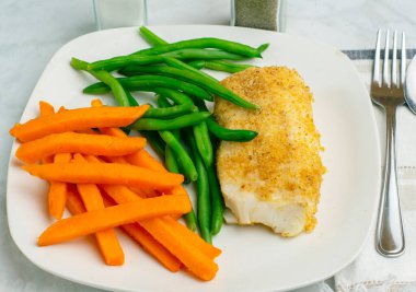  Tatlı patates kızartması ve taze fasulyeyle servis edilen kızarmış morina balığı.