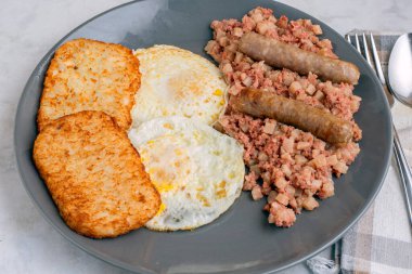 Kahvaltıda sosis ve mücver ile servis edilen mısır biftekli yumurta.