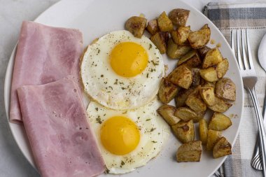 Maydanoz ve biberli sahanda yumurta dilimlenmiş jambon ve patates kızartması.