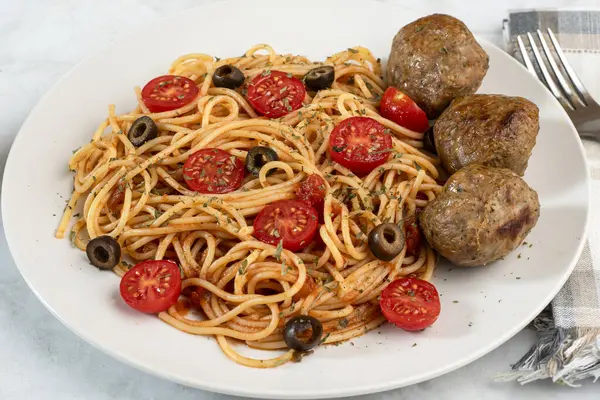  Domatesli spagetti üstü, zeytin ve kısmen İtalyan köfteleriyle servis edilir.