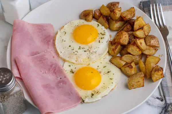 Maydanoz ve biberli sahanda yumurta dilimlenmiş jambon ve patates kızartması.