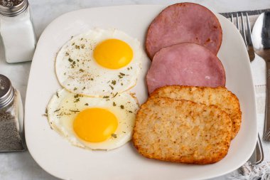  Yumurtanın üstünde otlar, kahvaltıda jambon ve patates kızartması var., 