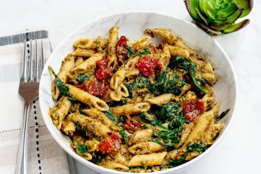 Pesto ile karıştırılmış makarna sotelenmiş domatesle servis ediliyor.