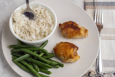 Pirinç ve yeşil fasulyeyle servis edilen tavuk butları.