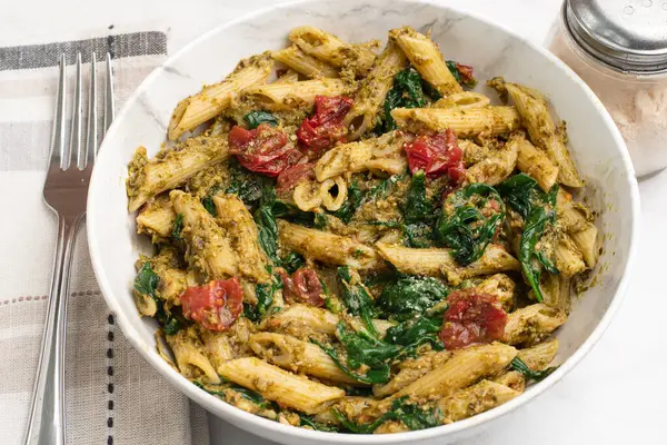 Pesto ile karıştırılmış makarna sotelenmiş domatesle servis ediliyor.