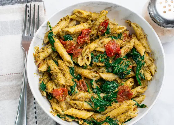 Pesto ile karıştırılmış makarna sotelenmiş domatesle servis ediliyor.
