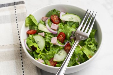  Doğranmış jambon, domates, marul ve salatalıklı taze salata.