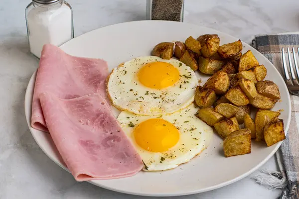 Maydanoz ve biberli sahanda yumurta dilimlenmiş jambon ve patates kızartması.
