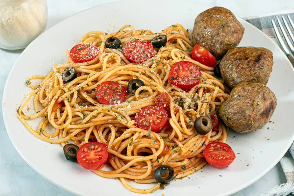  Domatesli spagetti üstü, zeytin ve kısmen İtalyan köfteleriyle servis edilir.