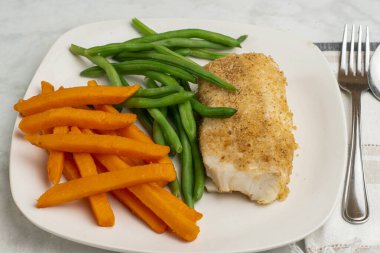  Tatlı patates kızartması ve taze fasulyeyle servis edilen kızarmış morina balığı.