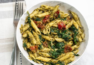 Pesto ile karıştırılmış makarna sotelenmiş domatesle servis ediliyor.