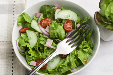 Doğranmış jambon, domates, marul ve salatalıklı taze salata.
