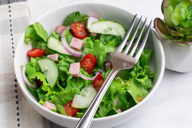 Doğranmış jambon, domates, marul ve salatalıklı taze salata.