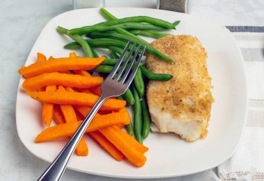  Tatlı patates kızartması ve taze fasulyeyle servis edilen kızarmış morina balığı.