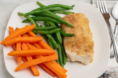  Tatlı patates kızartması ve taze fasulyeyle servis edilen kızarmış morina balığı.