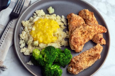 Patates püresiyle servis edilen tavuk kanatları kremalı mısır ve brokoli ile servis ediliyor.,