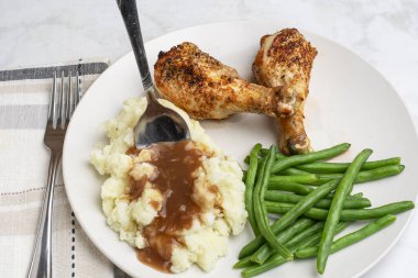  Patates püresi ve fasulyeli sos ile servis edilen tavuk budu.