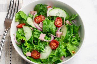  Doğranmış jambon, domates, marul ve salatalıklı taze salata.