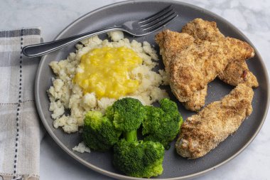 Patates püresiyle servis edilen tavuk kanatları kremalı mısır ve brokoli ile servis ediliyor.,