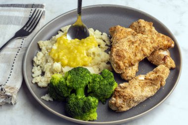 Patates püresiyle servis edilen tavuk kanatları kremalı mısır ve brokoli ile servis ediliyor.,