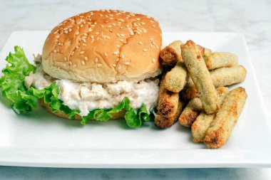 Brokoli kızartmasıyla servis edilen susamlı ekmeğin üzerinde ton balığı salatası.