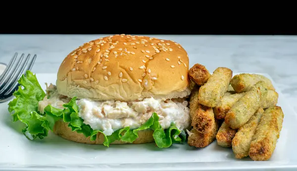 Brokoli kızartmasıyla servis edilen susamlı ekmeğin üzerinde ton balığı salatası.