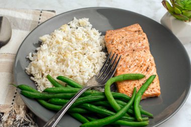 Baharatlı somon, yeşil fasulyeyle servis edilen sarımsaklı sebzeli pilav ile servis edilir.