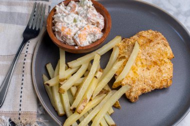  Karides deniz ürünleri salatası ve ev yapımı patates kızartmasıyla servis edilen kızarmış morina balığı.