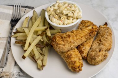  Ev yapımı patates kızartması ve makarna salatasıyla servis edilen tavuklar.