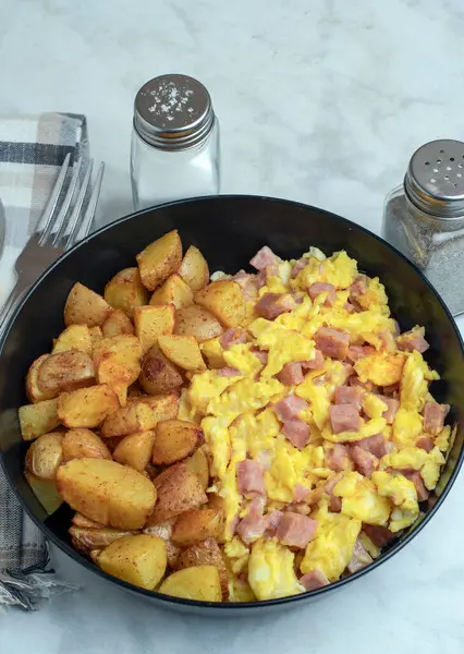 Çırpılmış yumurta ve konserve jambon yanında patates kızartması.