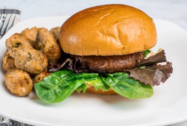 Portobello burger bahar karışımında dinleniyor sebzeler brokolili çöreğin üzerinde servis ediliyor.