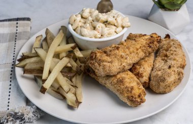  Ev yapımı patates kızartması ve makarna salatasıyla servis edilen tavuklar.