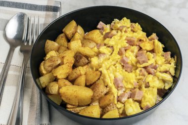 Çırpılmış yumurta ve konserve jambon yanında patates kızartması.