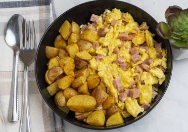 Çırpılmış yumurta ve konserve jambon yanında patates kızartması.
