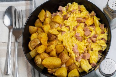 Çırpılmış yumurta ve konserve jambon yanında patates kızartması.